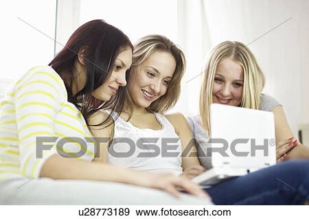 Stock Photo - Teenage girls using laptop on sofa. Fotosearch