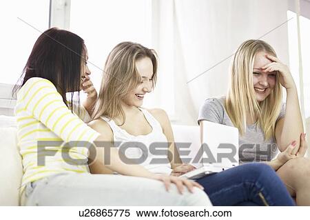 Teenage girls using laptop on sofa View Large Photo Image Stock Photography - Teenage girls using laptop on sofa. Fotosearch