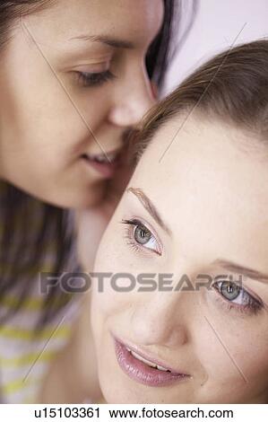 Stock Image - Teenage girls whispering to each other. Fotosearch