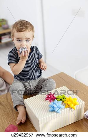 Toddler boy sitting with birthday present View Large Photo Image Stock Photo - Toddler boy sitting with birthday present. Fotosearch