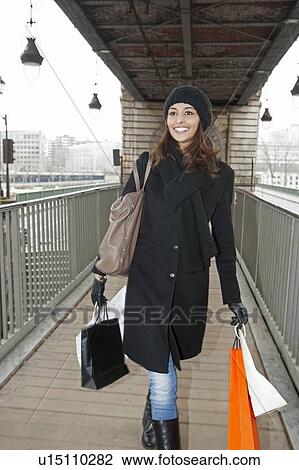 Stock Image - Woman carrying shopping bags on platform. Fotosearch