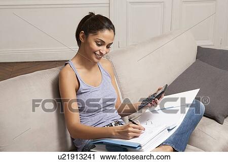 Woman doing homework on sofa View Large Photo Image Stock Image - Woman doing homework on sofa. Fotosearch