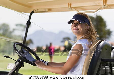 Stock Photo - Woman driving golf cart on course. Fotosearch