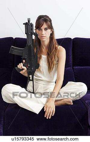 Woman holding machine gun on sofa View Large Photo Image Stock Photography - Woman holding machine gun on sofa. Fotosearch
