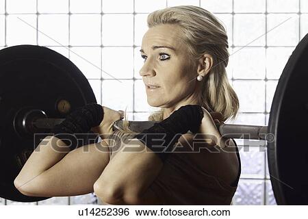 Stock Photograph - Woman lifting weights in gym. Fotosearch