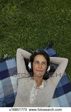 Woman listening to headphones in grass View Large Photo Image Stock Image - Woman listening to headphones in grass. Fotosearch