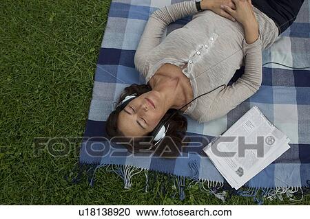 Woman listening to headphones in grass View Large Photo Image Stock Image - Woman listening to headphones in grass. Fotosearch