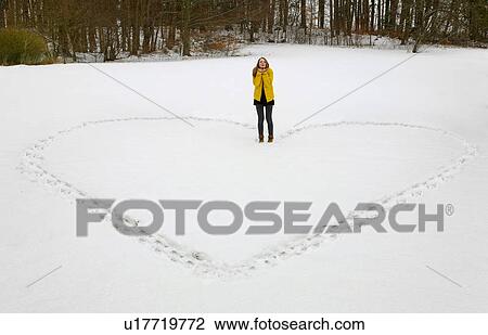 Stock Image - Woman making heart shape in snow. Fotosearch