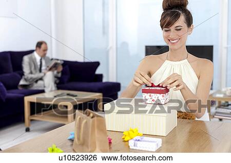 Woman opening presents at table View Large Photo Image Stock Photograph - Woman opening presents at table. Fotosearch