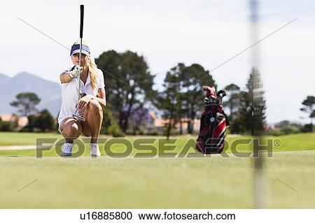 Stock Image - Woman playing golf on course. Fotosearch