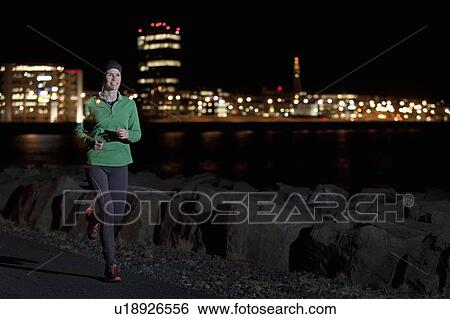 Stock Photograph - Woman running on waterfront at night. Fotosearch