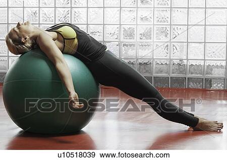 Stock Photo - Woman stretching with exercise ball. Fotosearch