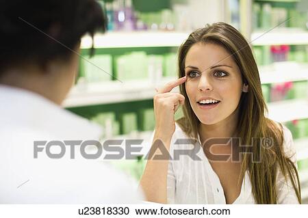 Stock Image - Woman talking to clerk in store. Fotosearch