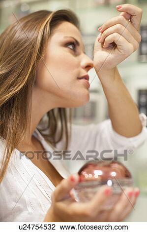 Stock Image - Woman trying on fragrances in store. Fotosearch