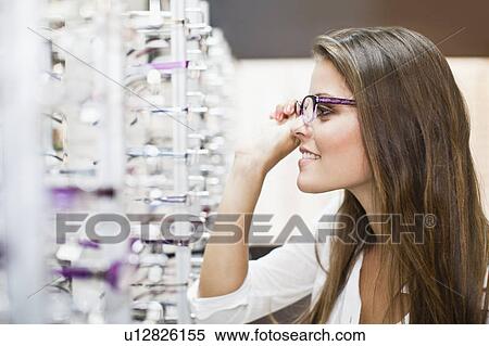Woman trying on glasses in store View Large Photo Image Stock Photography - Woman trying on glasses in store. Fotosearch