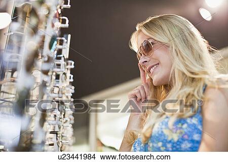 Picture - Woman trying on sunglasses in store. Fotosearch