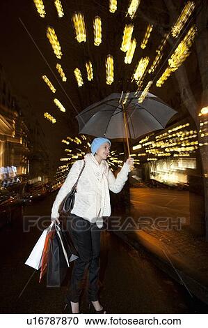 Stock Image - Woman under umbrella on city street. Fotosearch