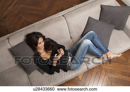 Woman using cell phone on sofa View Large Photo Image Stock Image - Woman using cell phone on sofa. Fotosearch