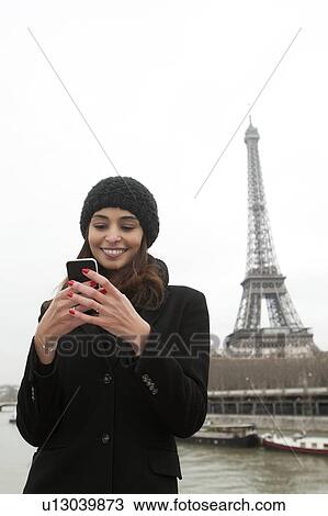 Stock Image - Woman using cell phone on waterfront. Fotosearch