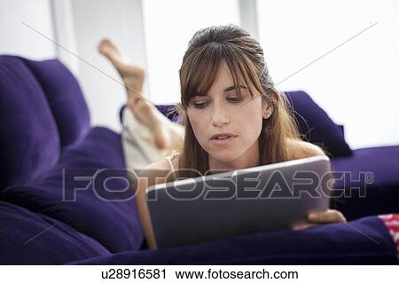 Woman using tablet computer on sofa View Large Photo Image Stock Image - Woman using tablet computer on sofa. Fotosearch