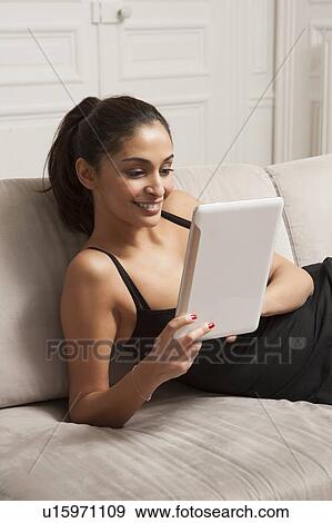 Woman using tablet computer on sofa View Large Photo Image Stock Photo - Woman using tablet computer on sofa. Fotosearch