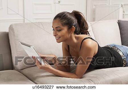 Woman using tablet computer on sofa View Large Photo Image Stock Photo - Woman using tablet computer on sofa. Fotosearch