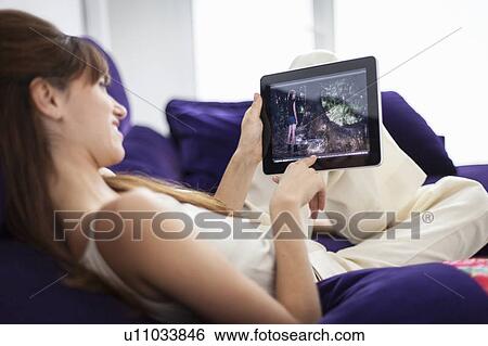 Stock Photograph - Woman using tablet computer on sofa. Fotosearch