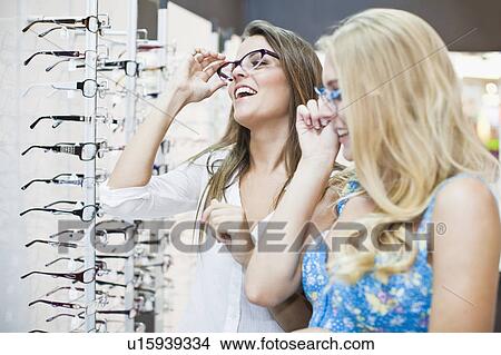 Women trying on glasses in store View Large Photo Image Picture - Women trying on glasses in store. Fotosearch