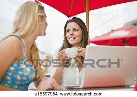 Picture - Women using laptop at sidewalk cafe. Fotosearch