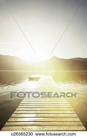 Stock Image - Wooden pier in still rural lake. Fotosearch