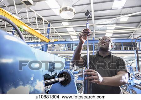 Picture - Worker checking machinery in factory. Fotosearch