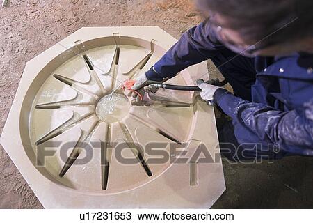 Stock Image - Worker cleaning mould in foundry. Fotosearch