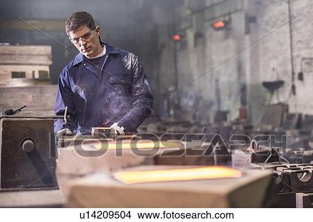 Picture - Worker examining moulds in metal foundry. Fotosearch