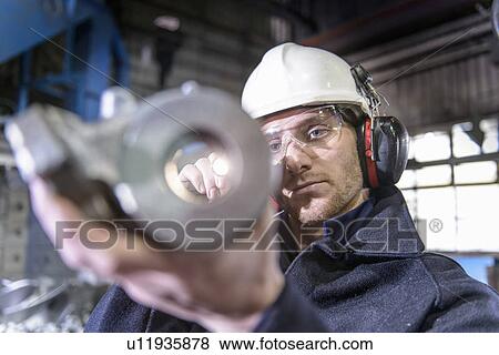 Worker inspecting metal in foundry View Large Photo Image Stock Photo - Worker inspecting metal in foundry. Fotosearch