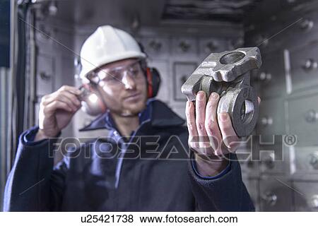 Worker inspecting metal in foundry View Large Photo Image Stock Photo - Worker inspecting metal in foundry. Fotosearch