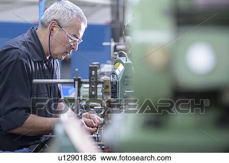 Stock Photograph - Worker polishing steel parts in factory. Fotosearch