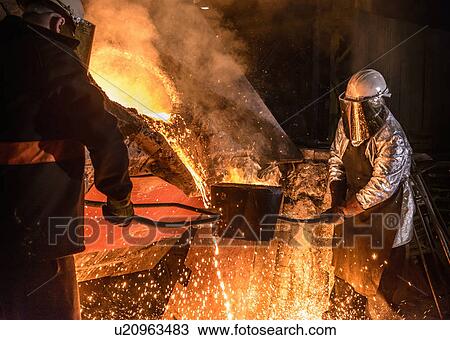 Stock Image - Worker pouring molten metal in foundry. Fotosearch
