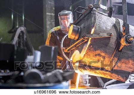 Worker pouring molten metal in foundry View Large Photo Image Stock Photograph - Worker pouring molten metal in foundry. Fotosearch
