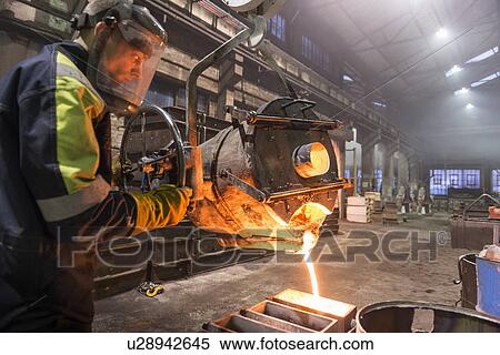 Worker pouring molten metal in foundry View Large Photo Image Stock Photography - Worker pouring molten metal in foundry. Fotosearch