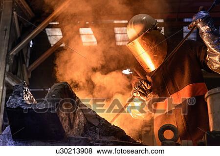 Worker stirring molten metal in foundry View Large Photo Image Stock Photo - Worker stirring molten metal in foundry. Fotosearch