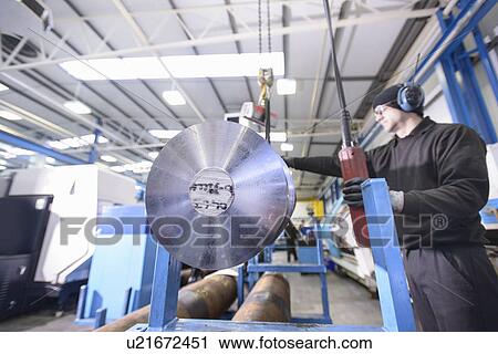 Stock Image - Worker using crane in steel factory. Fotosearch