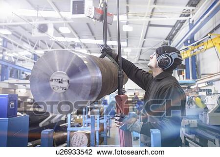 Stock Image - Worker using crane in steel factory. Fotosearch