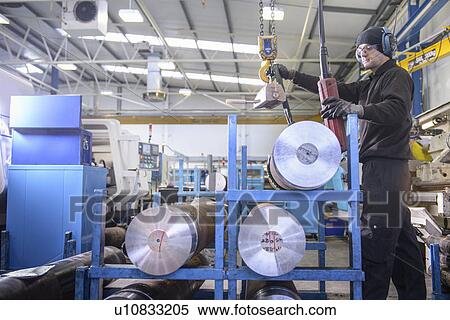 Stock Photography - Worker using crane in steel factory. Fotosearch