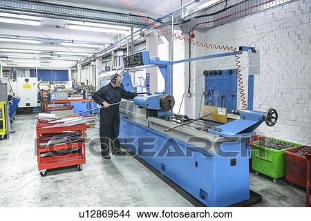 Picture - Worker using machinery in factory. Fotosearch