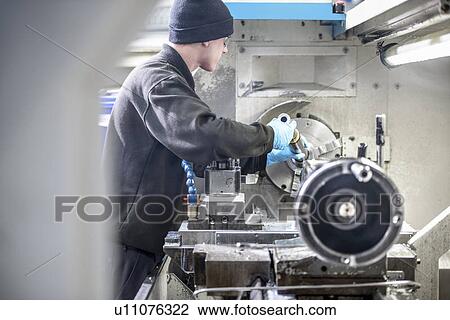 Stock Image - Worker using machinery in factory. Fotosearch