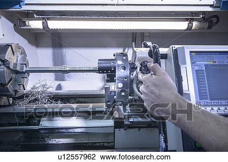 Stock Image - Worker using machinery in factory. Fotosearch