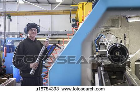 Stock Image - Worker using machinery in factory. Fotosearch