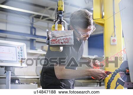 Worker using machinery in factory View Large Photo Image Stock Photo - Worker using machinery in factory. Fotosearch