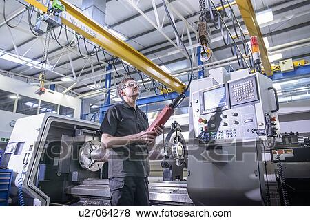 Stock Photo - Worker using machinery in factory. Fotosearch