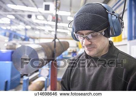 Worker wearing headphones in factory View Large Photo Image Stock Photograph - Worker wearing headphones in factory. Fotosearch